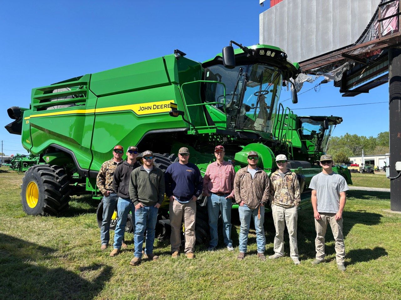 group of students and instructor in front a large combine