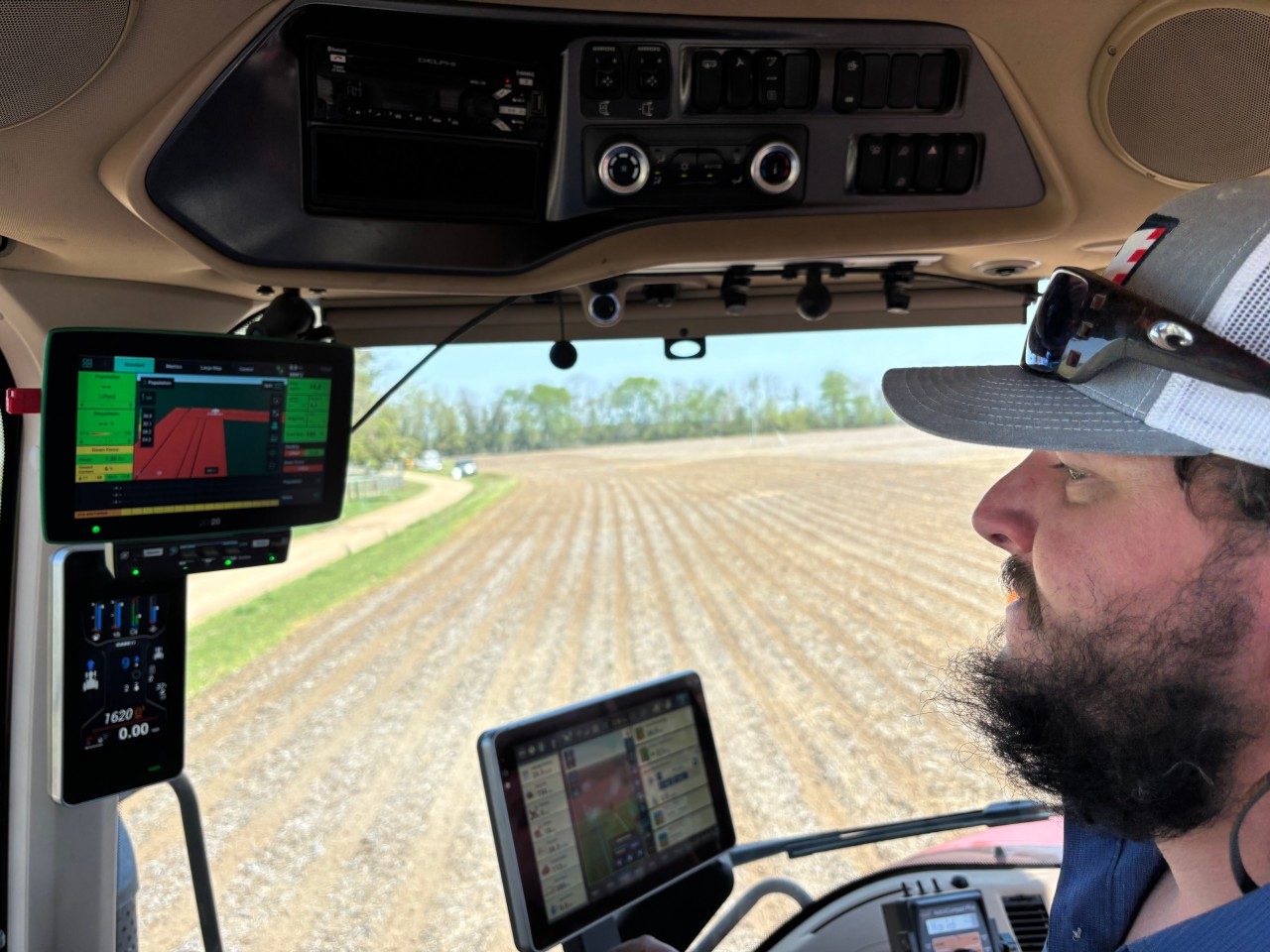 Farmer in tractor looking at GPS equipment and computer screen