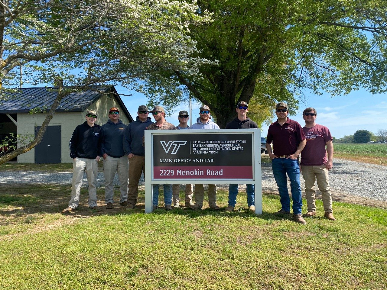 Students and faculty next to the main office sign at the AREC Office